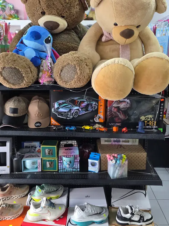 Estante de juguetes y regalos con peluches grandes encima, coches de control remoto y tazas