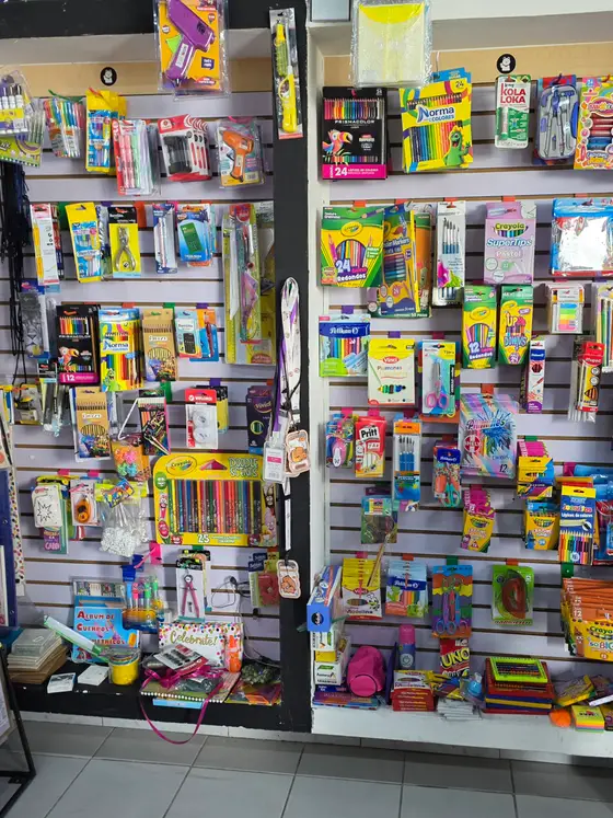 Pared de útiles: lápices de colores, plumones, crayones y material de dibujo colgado en su exhibidor